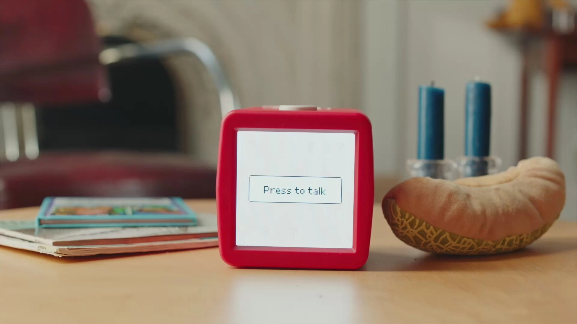 A red Stickerbox on a wooden table, its screen showing the words Press to talk
